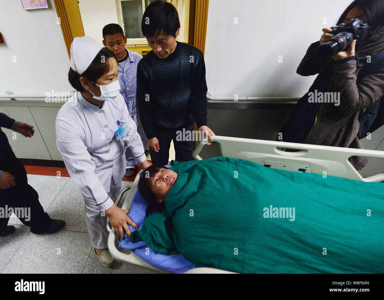 Li Qingzhong, centre, encourage son fils Li Kai, qui a reçu un diagnostic de l'urémie et obtenu un rein de sa mère, avant la transplantation rénale Banque D'Images