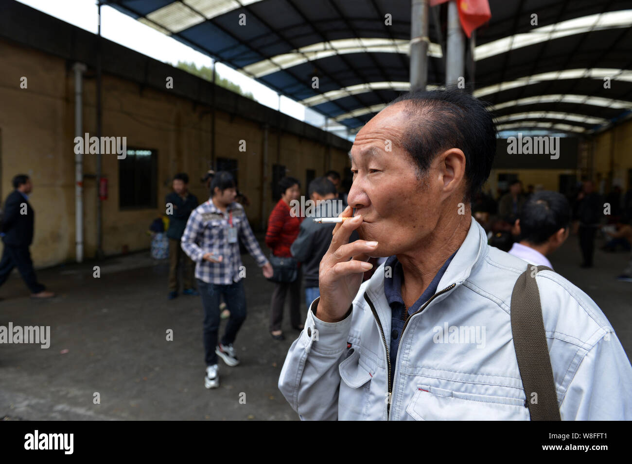 --FILE--Un homme fume une cigarette à un marché de l'emploi dans la ville de Nanjing, Jiangsu province de Chine orientale, 8 octobre 2015. Les experts de la santé mondiale demandent fo Banque D'Images