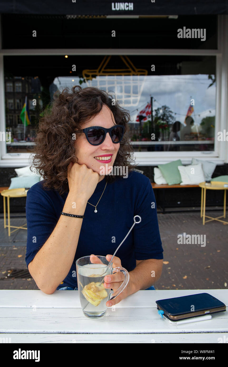 Den Haag. Een jonge vrouw drinkt gemberthee op een terras.. Foto : Gerrit de Heus. Les Pays-Bas. Une jeune femme à boire le thé au gingembre. Photo : Gerrit d Banque D'Images