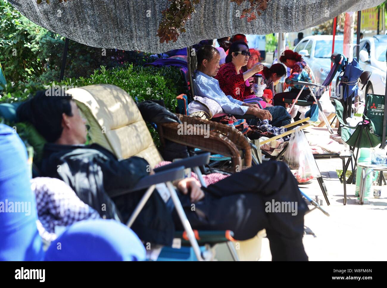 Les grands-parents chinois s'asseoir sur les chaises en face de la maternelle brun comme ils l'espoir d'obtenir des places pour leurs enfants avant l'inscription à Pékin, Chi Banque D'Images