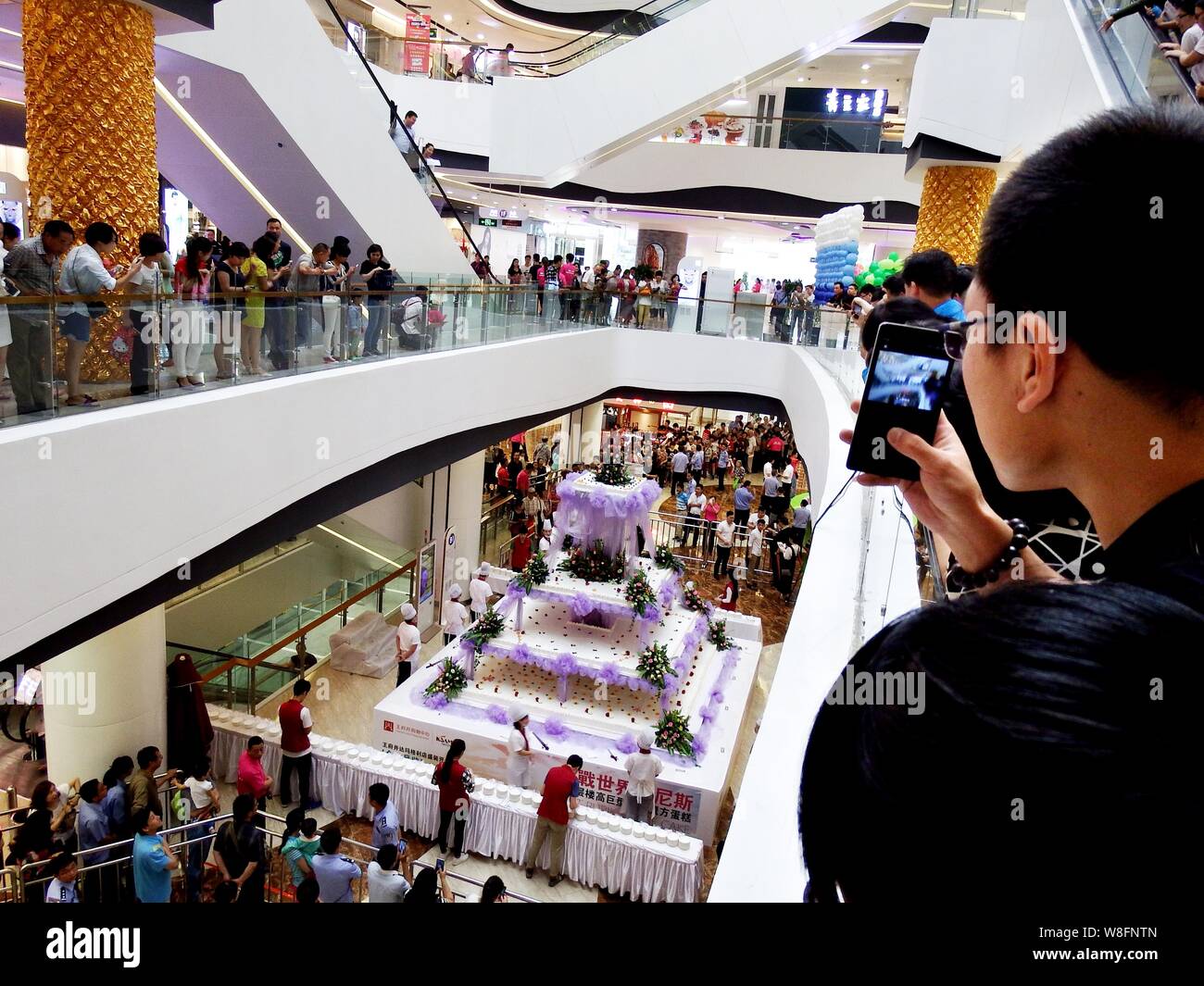 Les visiteurs d'oeil à un immense gâteau, avec 5 mètres de hauteur, 4 mètres de longueur et de largeur, à un centre commercial dans la ville de Luoyang, Chine centrale's Henan provinc Banque D'Images