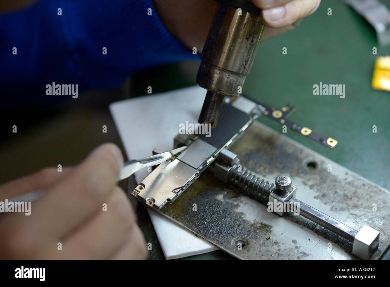 Un technicien chinois chauffe la puce de stockage d'origine pour l'enlever de un circuit intégré d'un Apple iPhone 6 16Go en plus du smartphone Banque D'Images