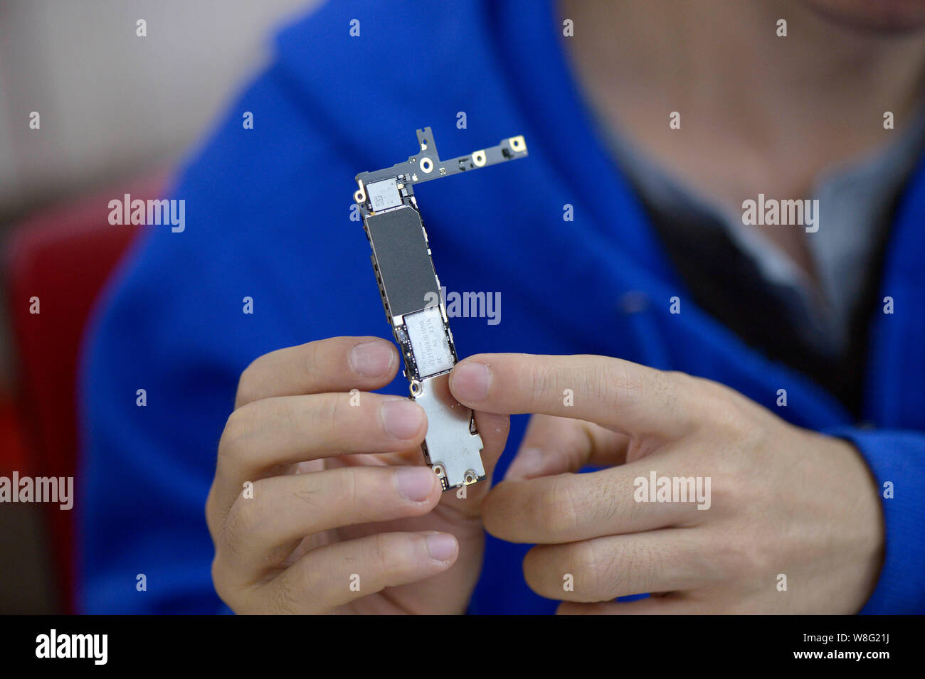 Un technicien chinois présente la puce de stockage d'origine sur un circuit intégré d'un Apple iPhone 6 16GB téléphone intelligent Plus en cours de mise à niveau pour Stora Banque D'Images