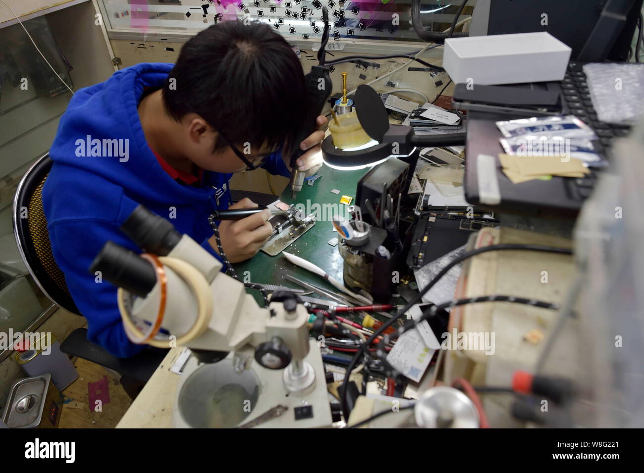 Un technicien chinois chauffe le points de soudure sur un circuit intégré d'un Apple iPhone 6 16GB téléphone intelligent Plus en cours de mise à niveau pour le stockage bo Banque D'Images