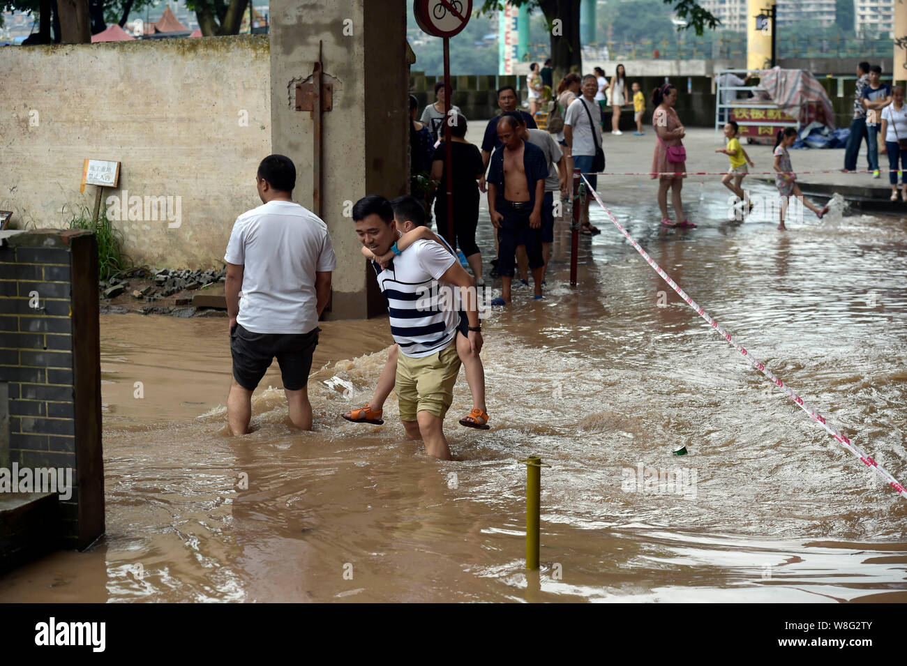 Un père avec son fils à l'arrière des promenades dans inondation causée par les fortes pluies à Chongqing, Chine, 30 juin 2015. Quatre jours de fortes pluies ont causé de sev Banque D'Images