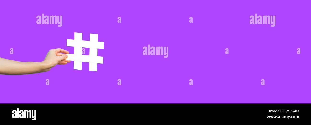 Social media concept. closeup of human hand holding et montrant de grandes hashtag big white signe. piscine, studio shot isolé sur fond violet violet Banque D'Images