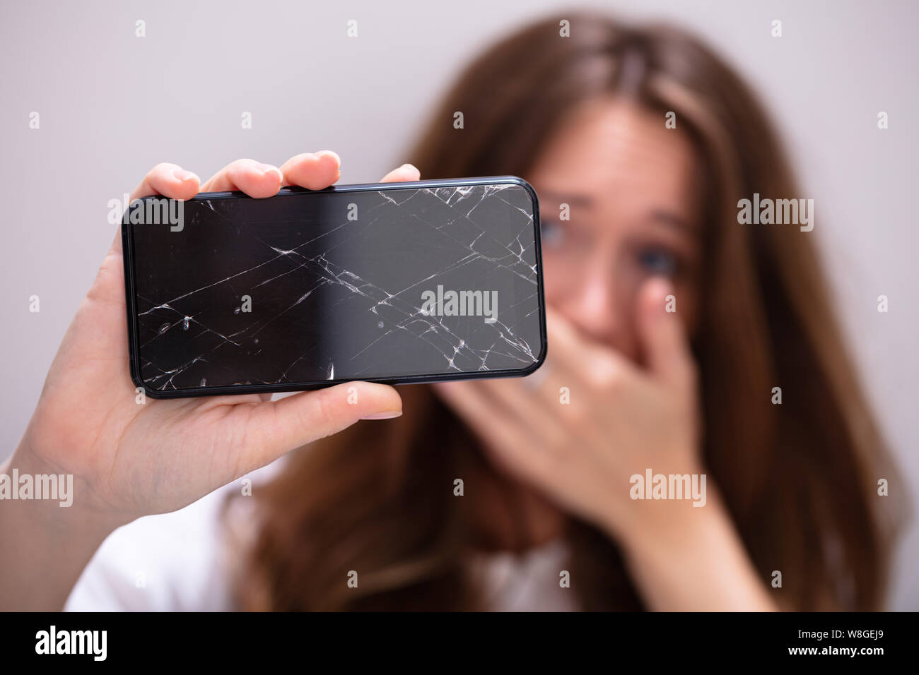 Woman Holding Smartphone avec écran fissuré Banque D'Images