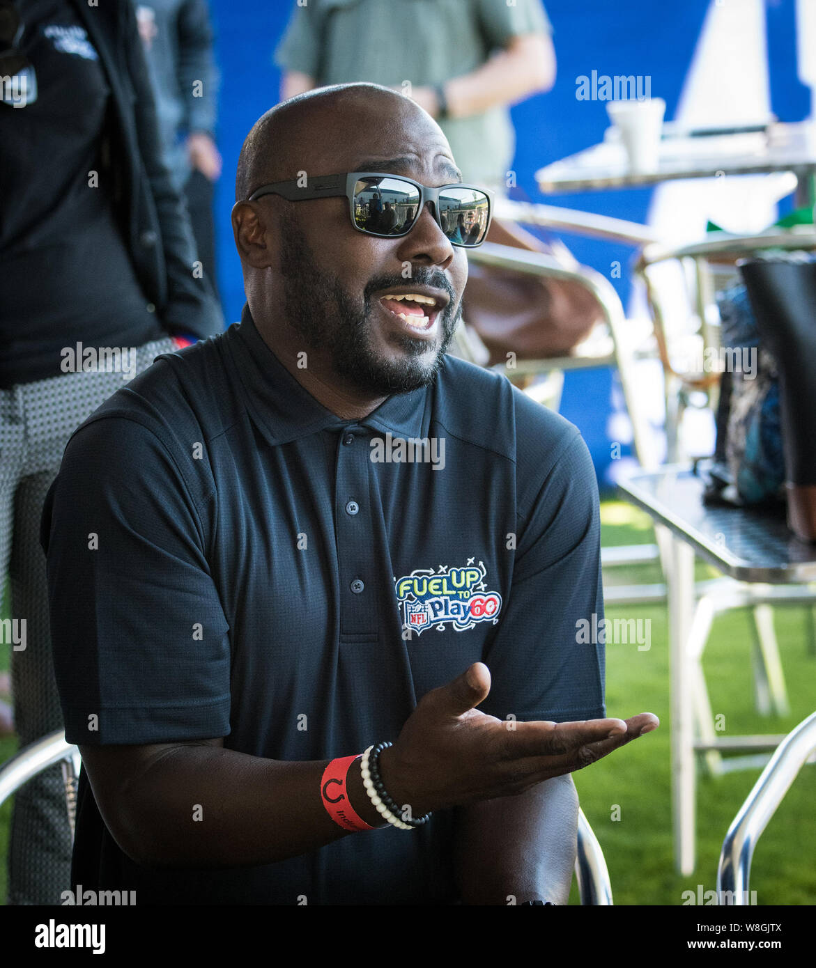 Les lunettes de soleil sont portées par la renommée de la NFL running back Marshall Faulk comme il parle aux enfants au sujet de l'exercice Banque D'Images