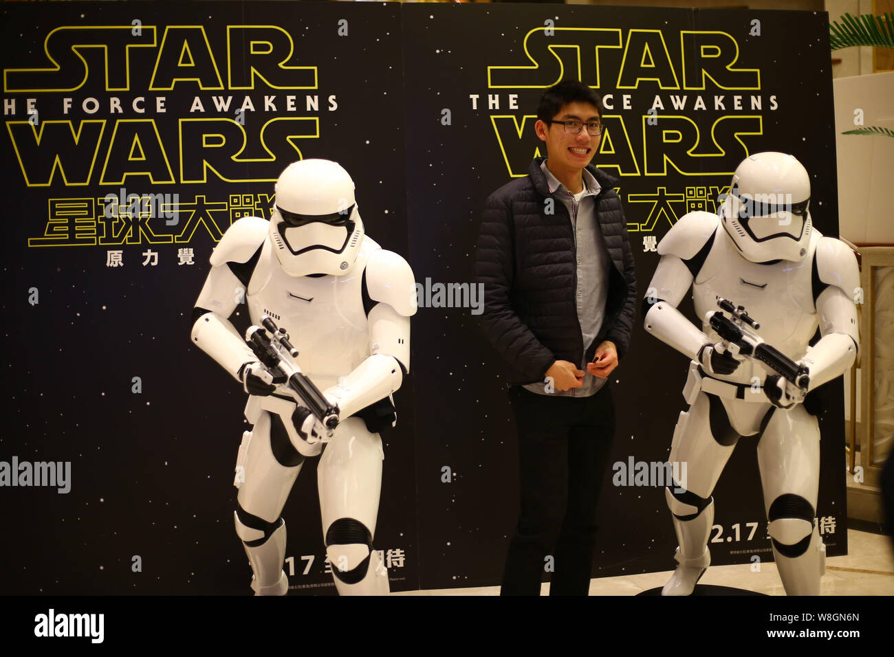 Un filmgoer chinois pose avec des modèles de Stormtroopers devant une affiche de film 'Star Wars : The Force éveille' dans un cinéma à Shanghai, Chine, 25 Banque D'Images