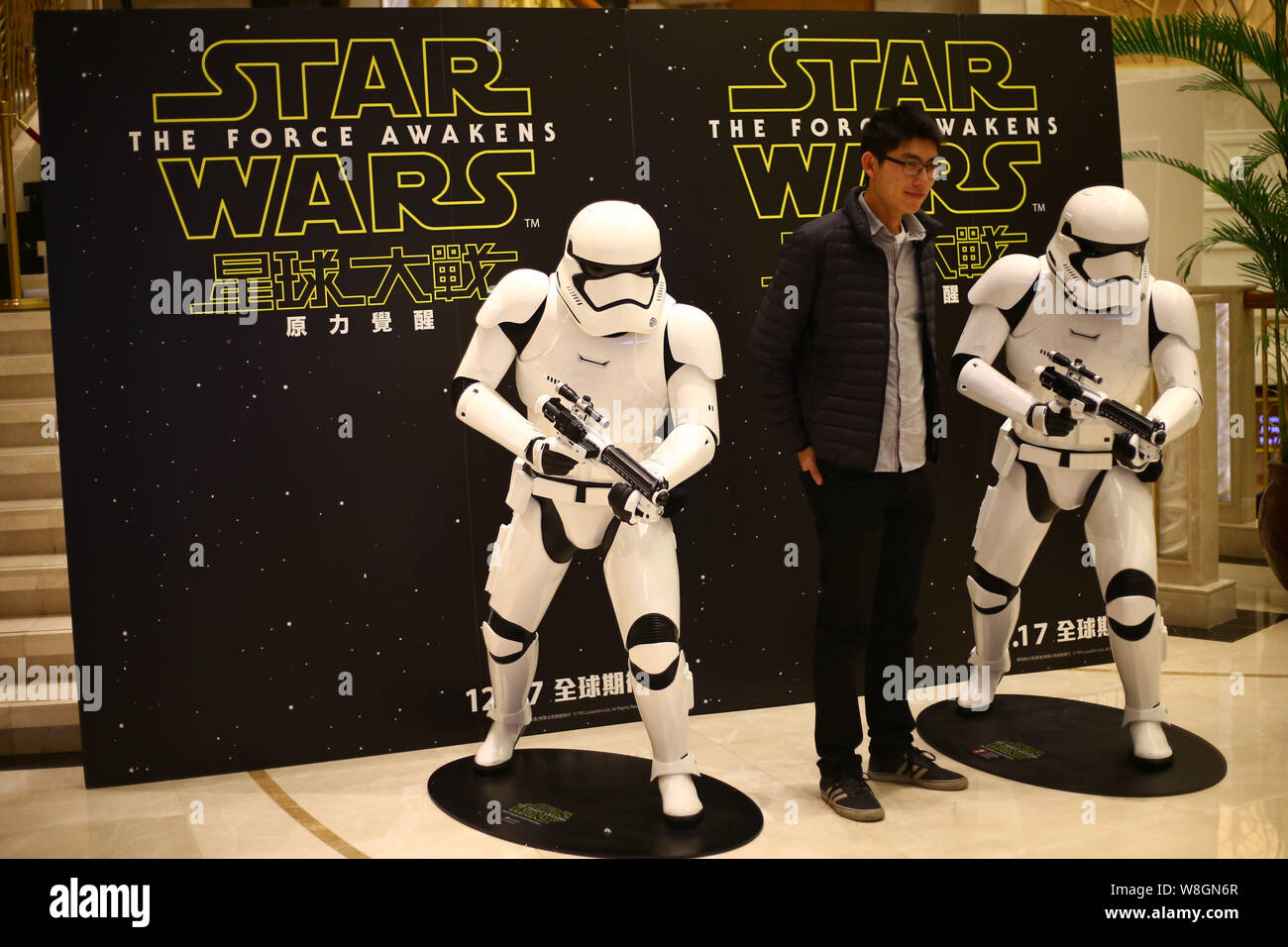 Un filmgoer chinois pose avec des modèles de Stormtroopers devant une affiche de film 'Star Wars : The Force éveille' dans un cinéma à Shanghai, Chine, 25 Banque D'Images