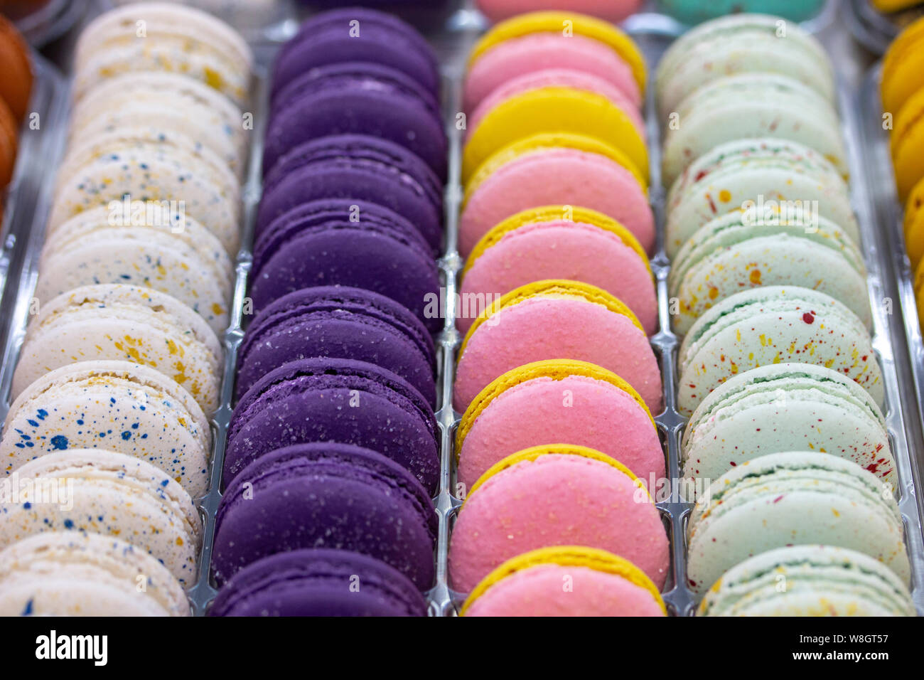 Macarons français sont disposés en rangées de lisse blanc rose violet. Pâte à macaron gâteaux à la crème, les biscuits sucrés showcase confiserie Banque D'Images