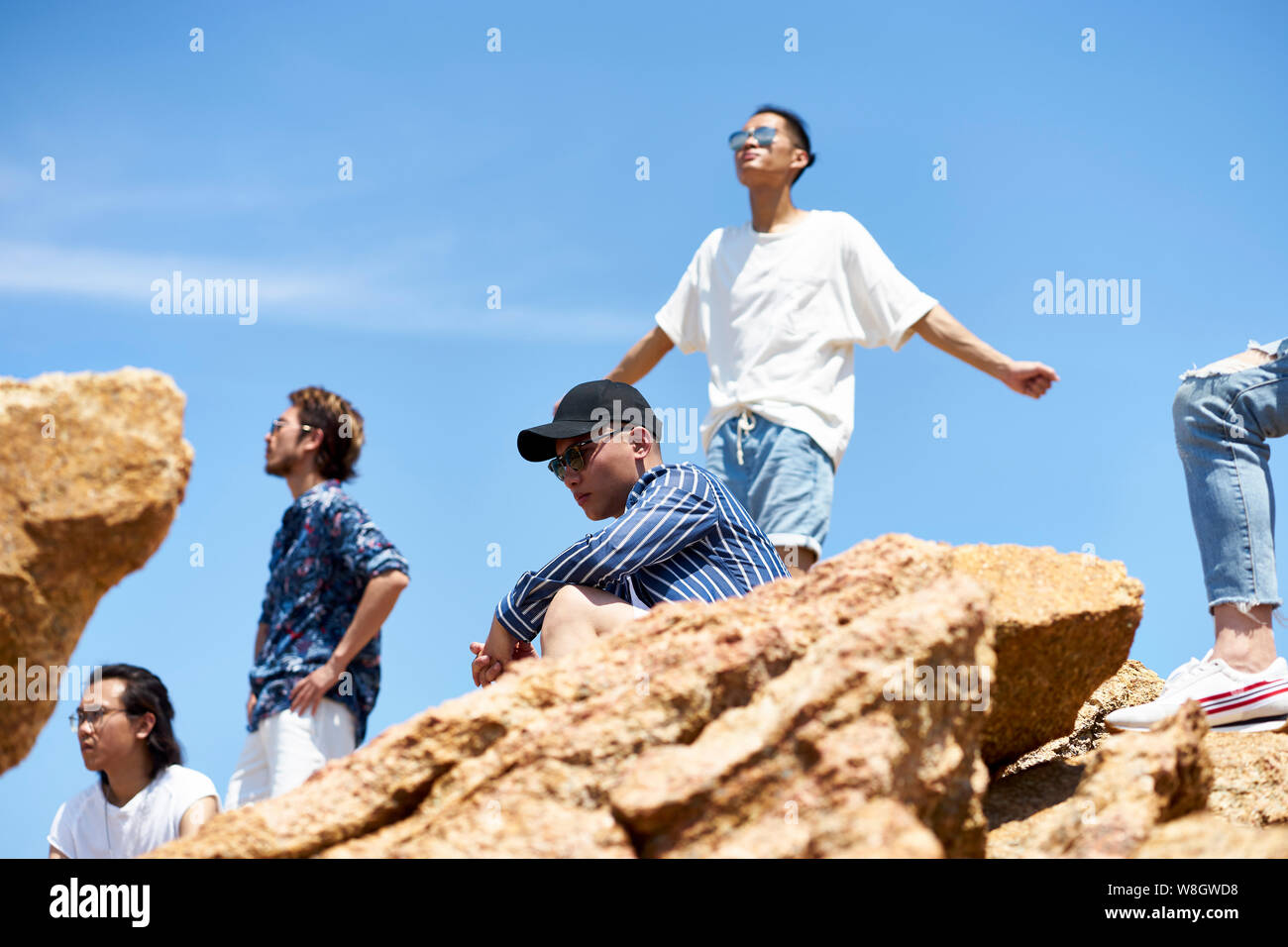 Groupe de jeunes adultes asiatiques hommes debout sur le haut des roches contre ciel bleu profitant du soleil et de l'air frais Banque D'Images