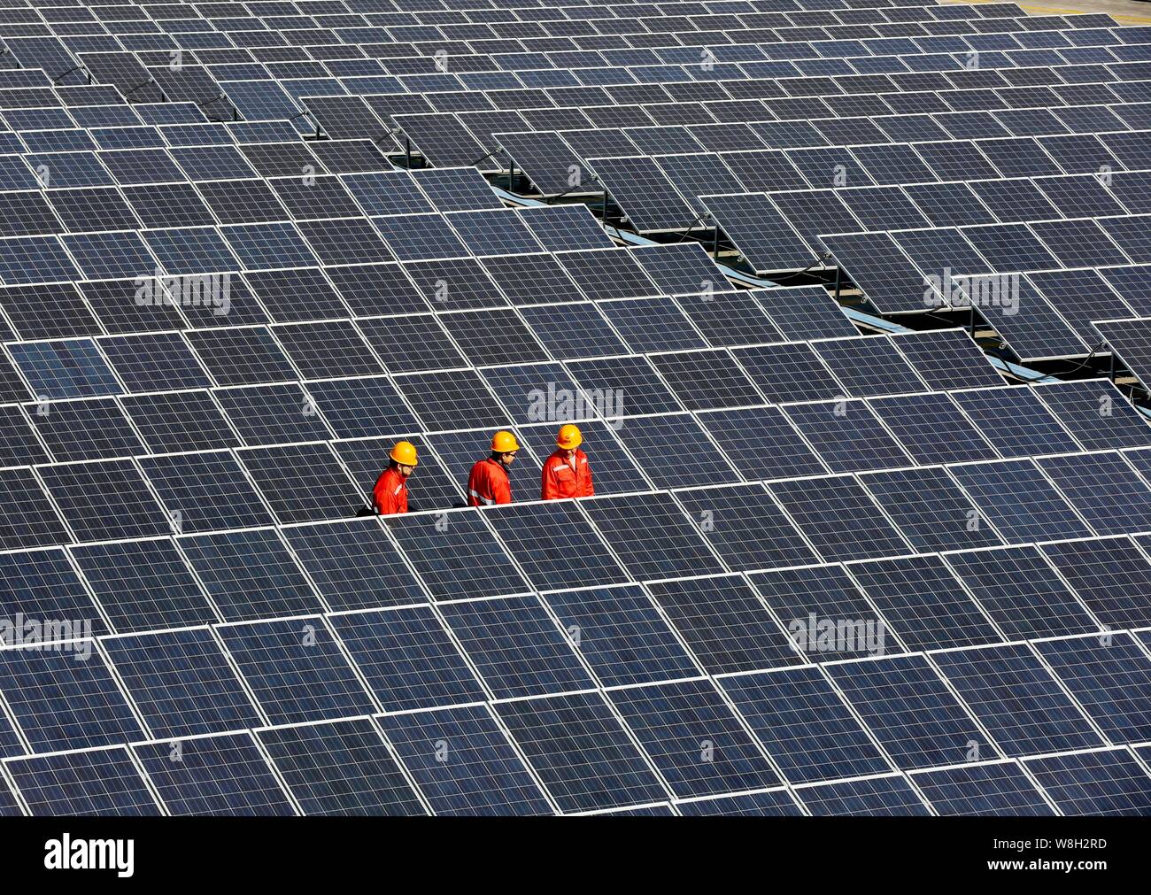 --FILE--travailleurs chinois vérifier des panneaux solaires installés sur le toit d'un bâtiment de l'usine à l'usine du groupe Ming Xin Feng dans Zhouquan Tongxi, ville Banque D'Images