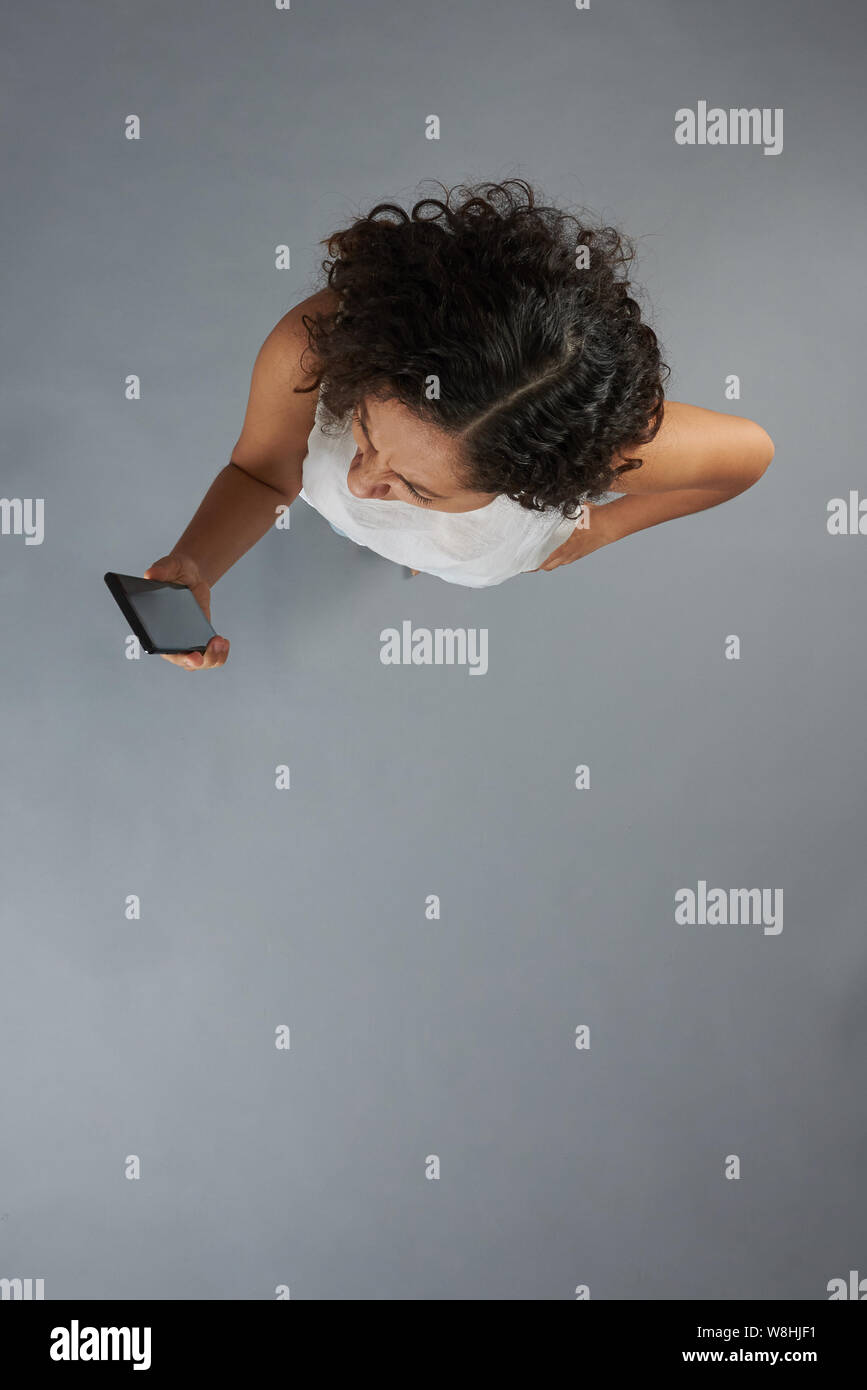 Brunette woman hold ci-dessus smartphone vu de dessus en arrière-plan studio Banque D'Images