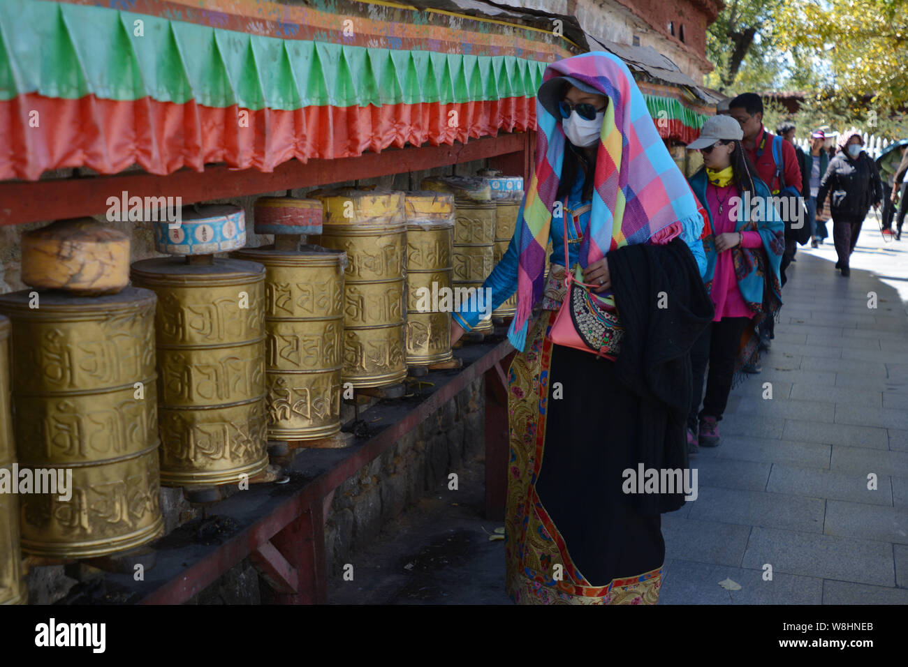 --FILE--une femme habillé en costume tibétain et des touristes dans la rotation des roues de prière Palais du Potala à Lhassa, le sud-ouest de la Chine, région autonome du Tibet, 1 Banque D'Images