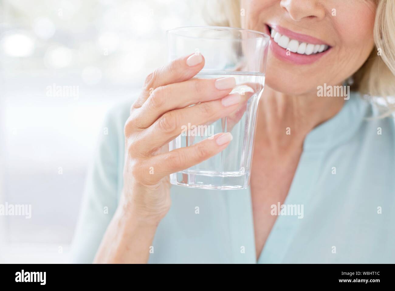 Young woman smiling avec verre d'eau. Banque D'Images