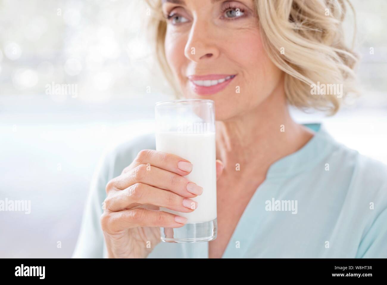 Young woman smiling avec verre de lait. Banque D'Images