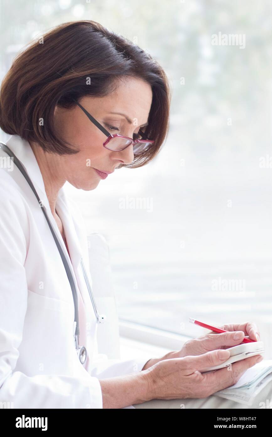 Femme médecin portant des lunettes avec l'appareil. Banque D'Images