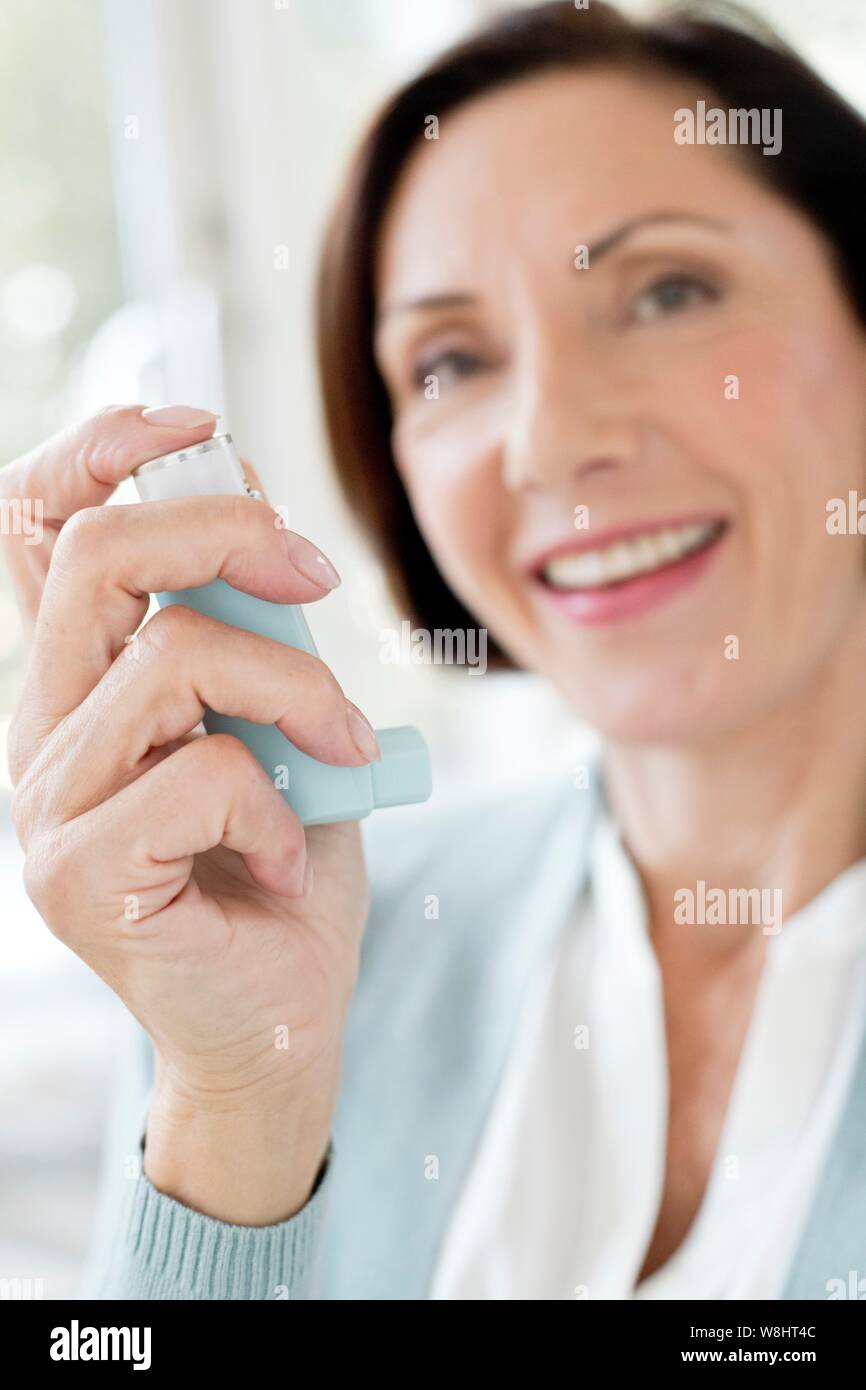 Mature Woman using inhaler. Banque D'Images
