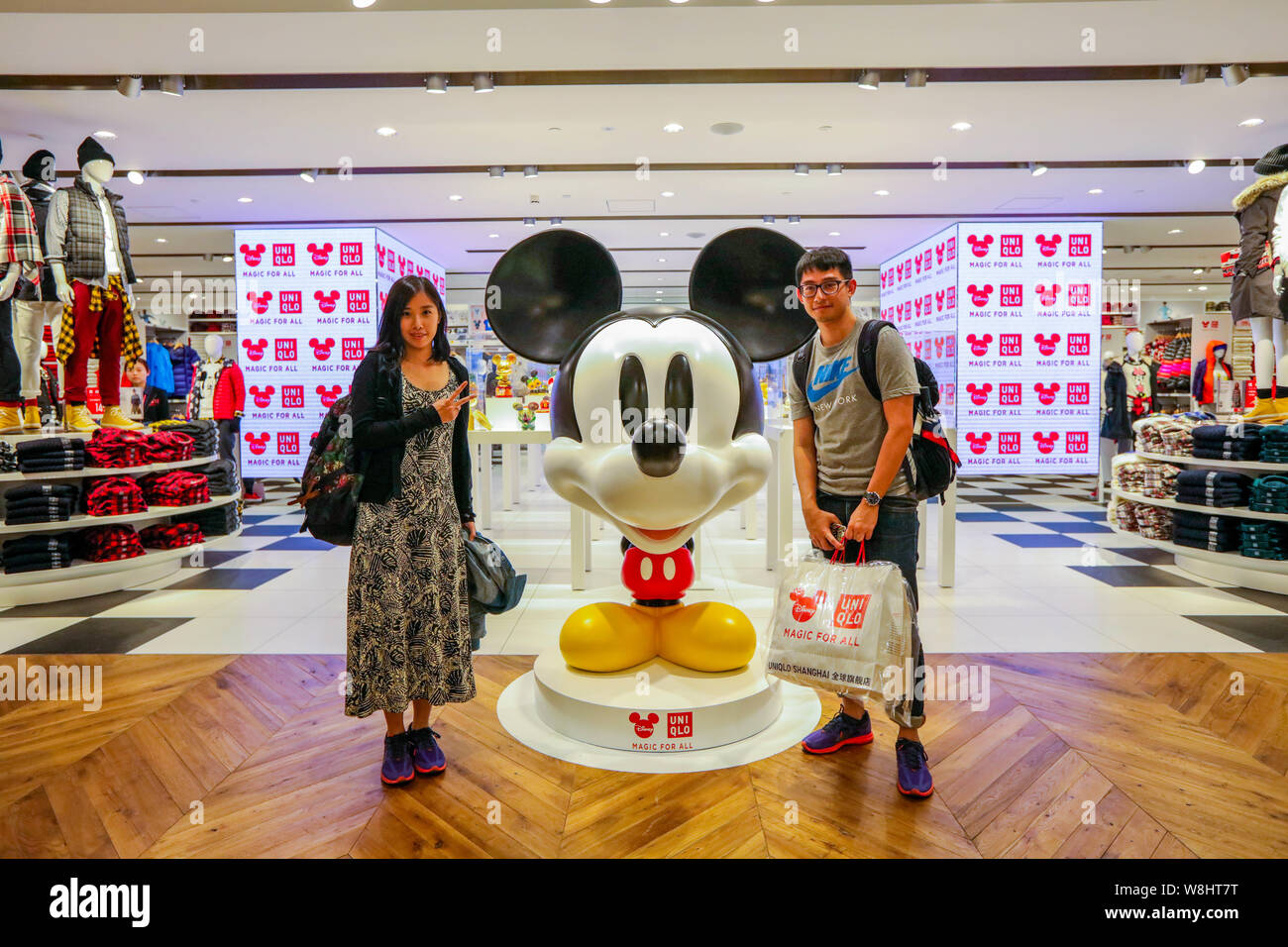 Les clients posent avec une statue de Mickey Mouse Disney l'Uniqlo au concept store d'inspiration à Shanghai, Chine, le 29 septembre 2015. Uniqlo, le populaire J Banque D'Images