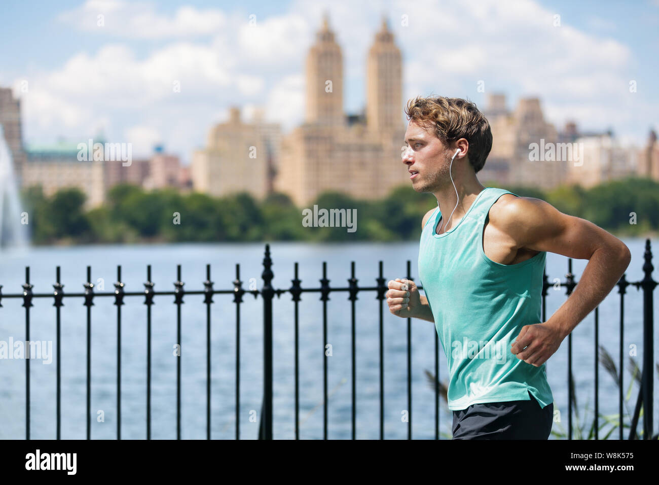 Runner mâle tournant à New York Central Park en été voyage le long de la lake avec vue sur les gratte-ciel fond. New Yorker vivre une vie en santé et en forme. Banque D'Images
