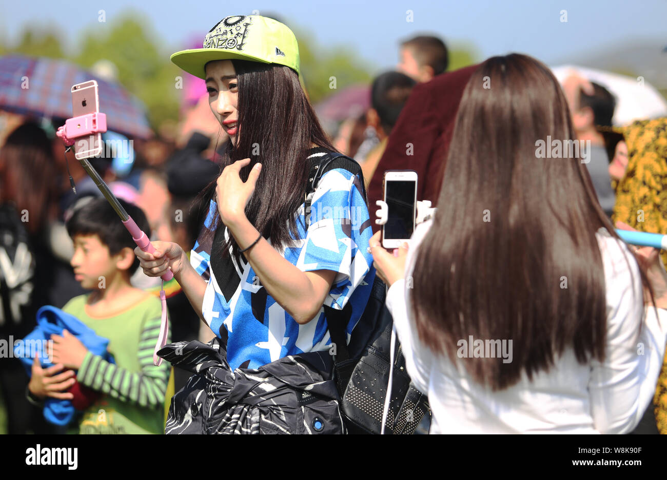 --FILE--Les jeunes filles chinoises prendre vos autoportraits avec leurs smartphones et iPhone Apple à un bâton selfies scenic spot à Zhumadian Ville, Centre de la Chine's Hen Banque D'Images