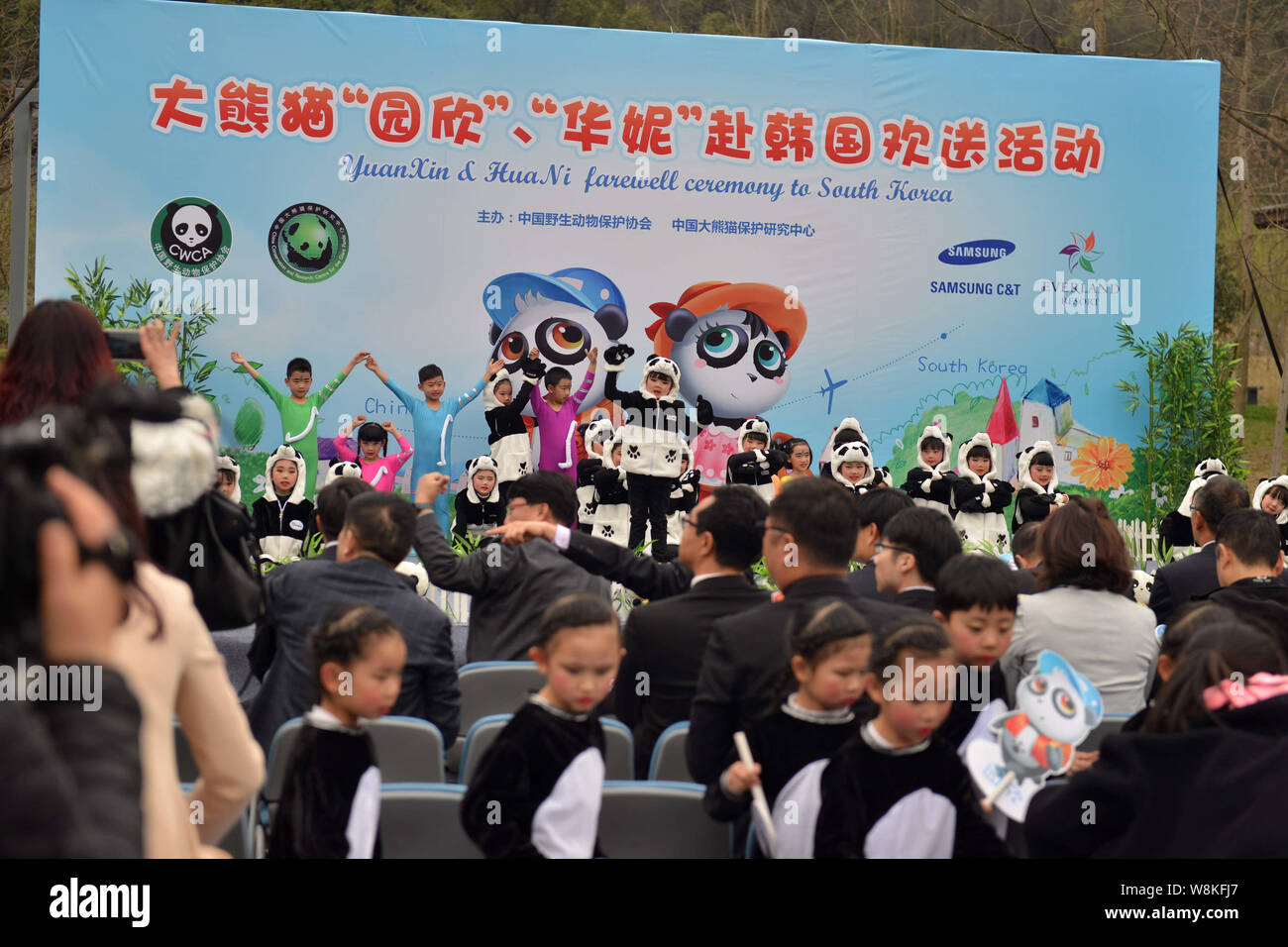 Les jeunes étudiants chinois vêtus de costumes panda effectuer au cours de la cérémonie d'adieu pour les pandas géants Yuan Xin Hua et ni à la base de l'Dujiangyan Banque D'Images
