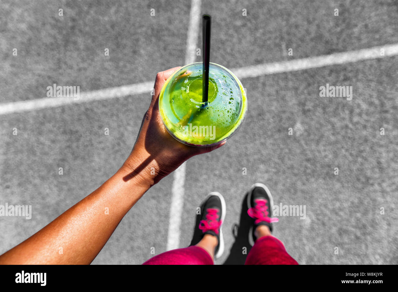 Smoothie vert Femme buvant tasse en plastique de petit-déjeuner à emporter repas pour aller après matin couru dans les rues de la ville. De vie sain personne sportive pov de hand holding glass avec des chaussures de course à pieds. selfies Banque D'Images