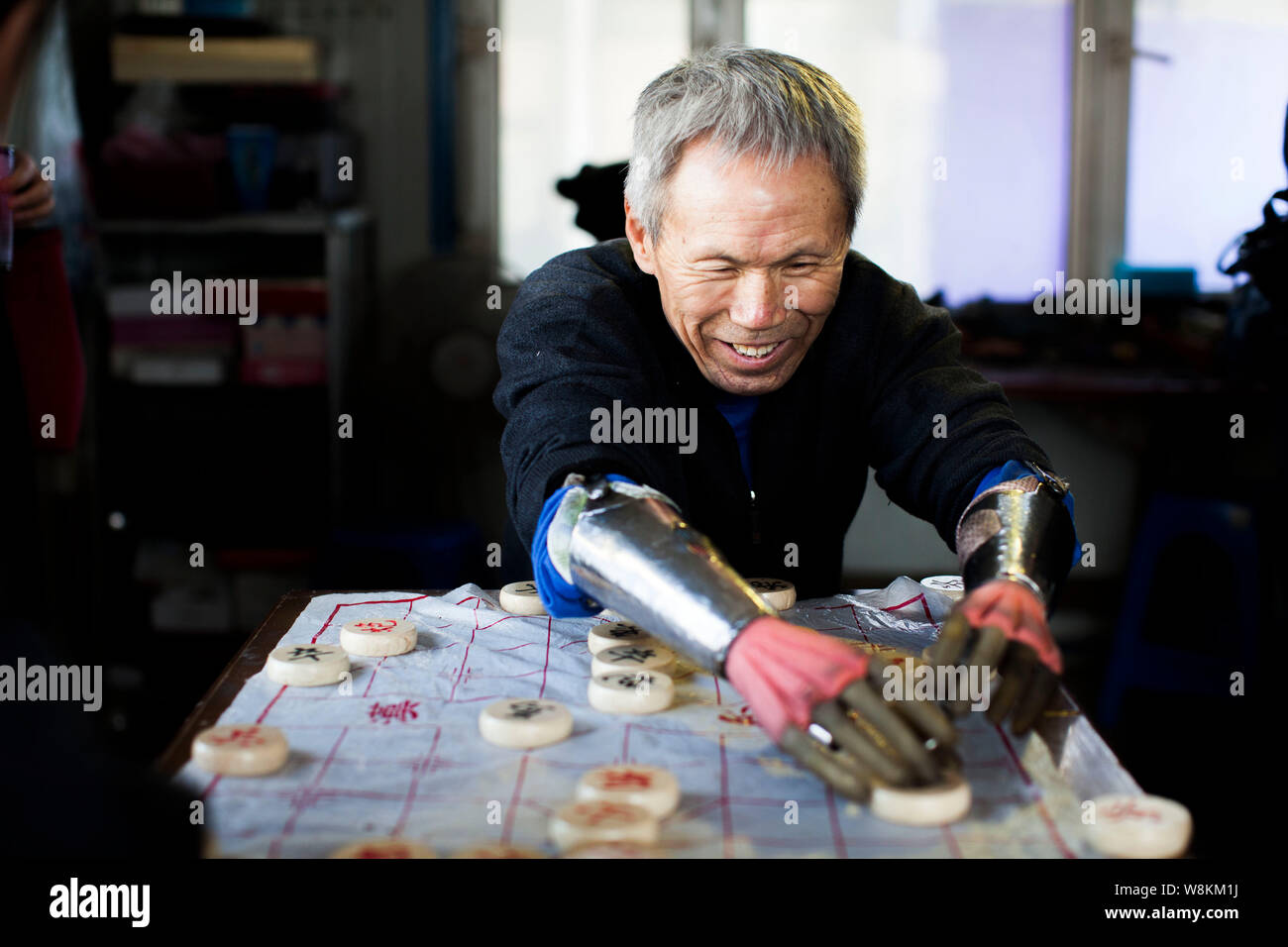 63-year-old Sun Jifa agriculteur sans bras qui est équipé de ses mains mécanique maison joue aux échecs chinois à Guanma ville, village, Kouqian Yo Banque D'Images