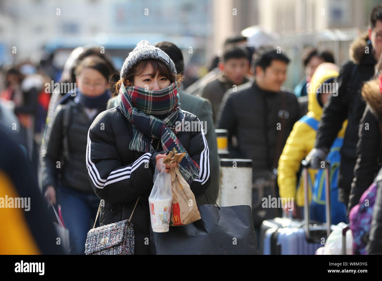 Les passagers chinois habillé chaudement contre la vague de froid transportant leurs bagages arrivent à l'Hotel qu'ils reviennent au pays pour Banque D'Images