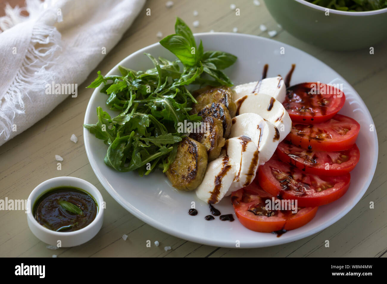 Salade Caprese avec tomates, mozzarella, basilic et aubergines grillées sur plaque blanche. Vue de dessus sur l'arrière-plan Banque D'Images