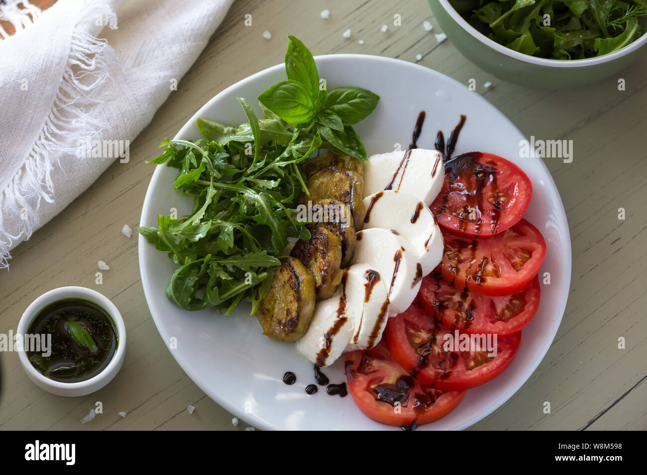 Salade Caprese avec tomates, mozzarella, basilic et aubergines grillées sur plaque blanche. Vue de dessus sur l'arrière-plan Banque D'Images