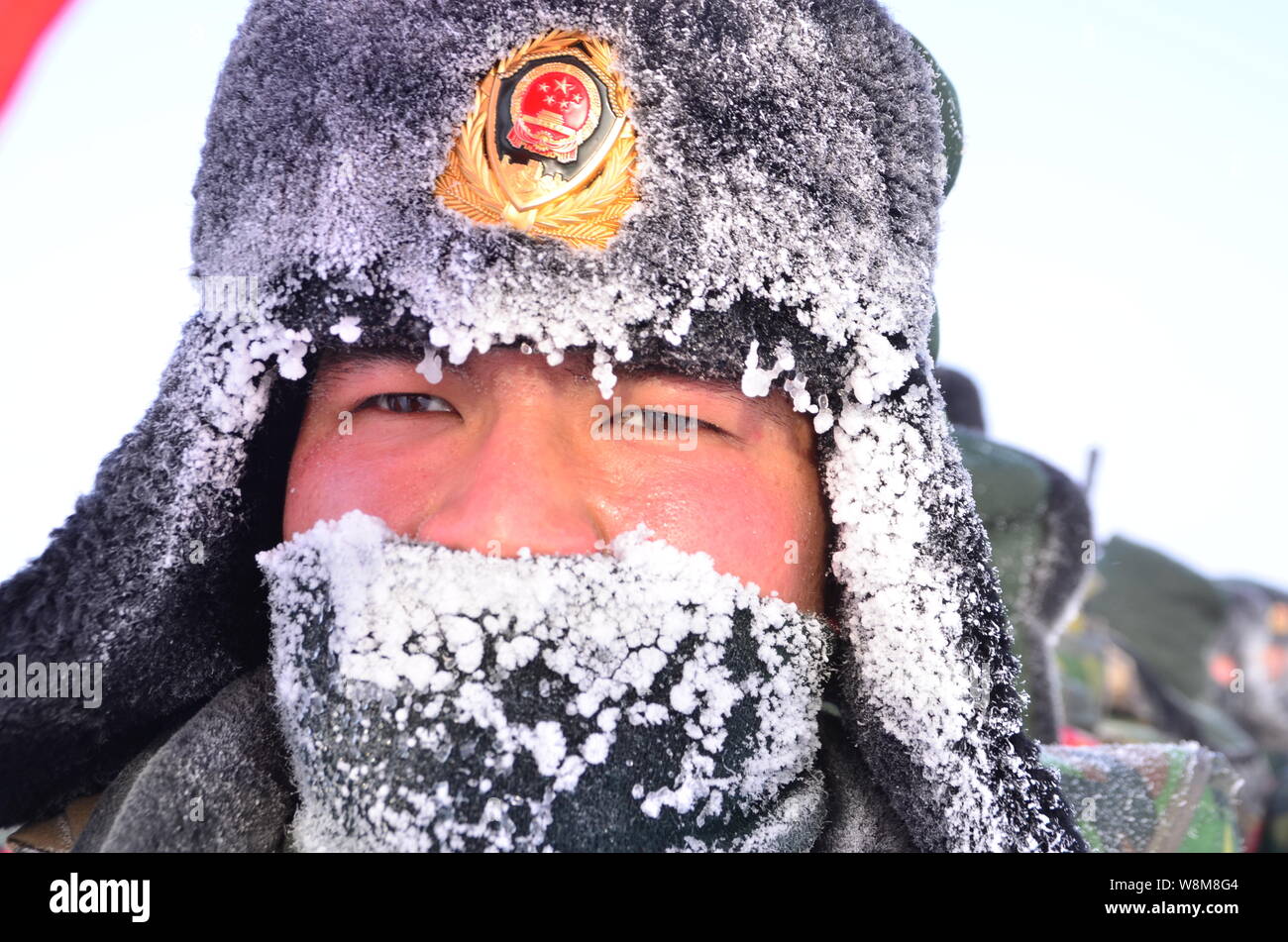 La glace et le givre sont vus sur le masque et le chapeau d'un agent de  police paramilitaire chinois comme lui et d'autres sur mars la neige en  direction de la forêt