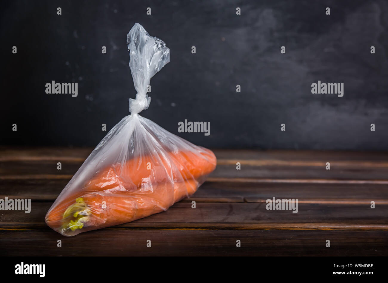 Plastique concept gratuitement les carottes dans un sac en plastique sur un fond brun avec copie espace Banque D'Images