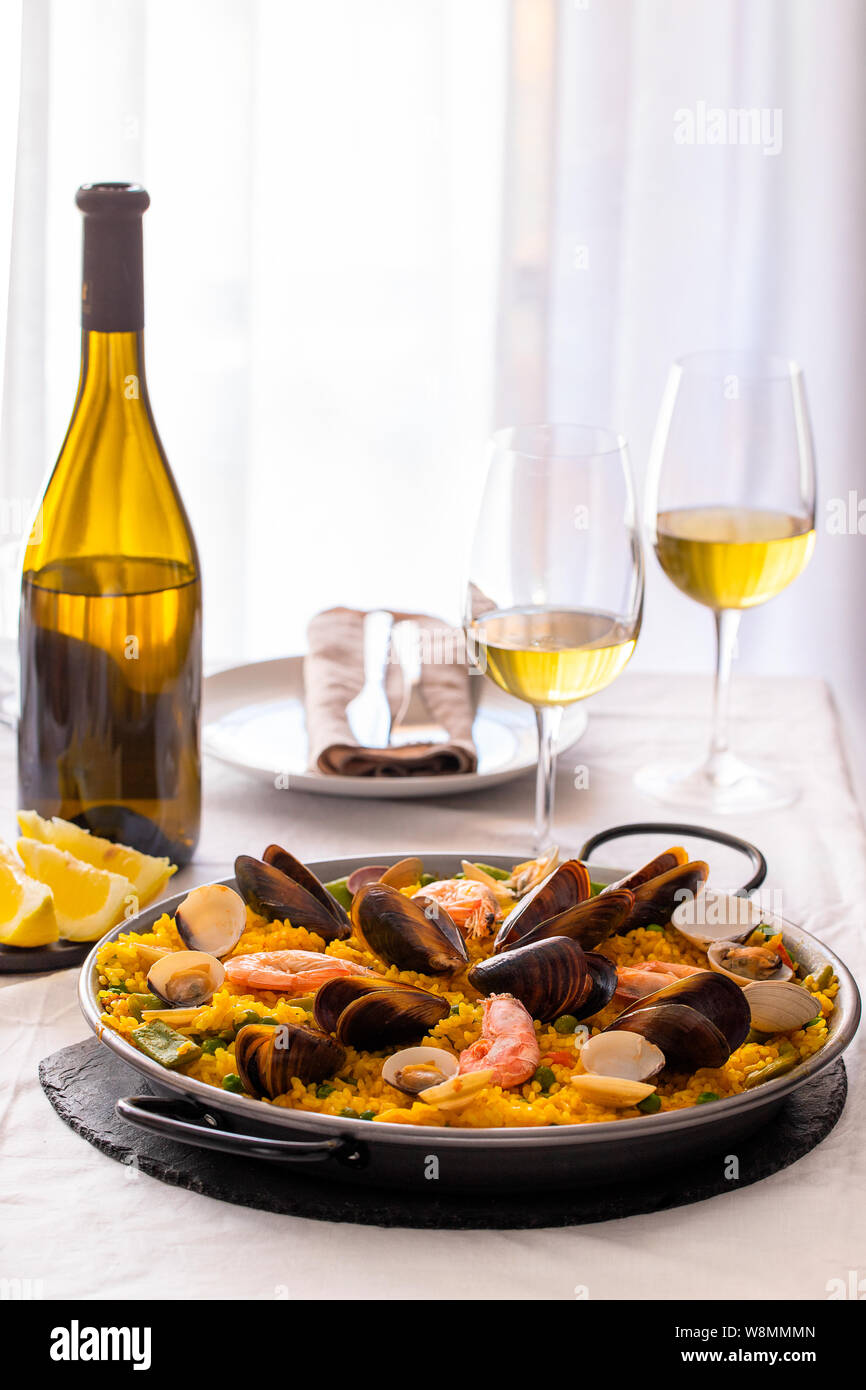 Paella aux fruits de mer, fameux plat de riz espagnol traditionnel servi dans la poêle avec le vin blanc. Paella Valenciana avec crevettes roses, les palourdes et les moules sur le sa Banque D'Images