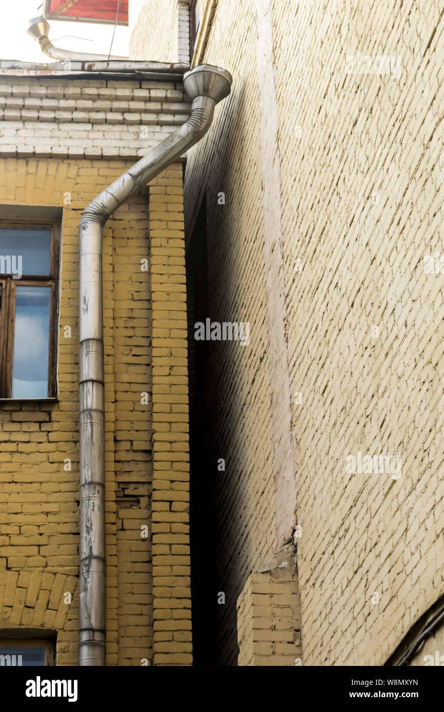 Gouttière posée sur un mur de brique jaune. La cour de la vieille maison. Site sur l'architecture, les drains, les communications. Banque D'Images