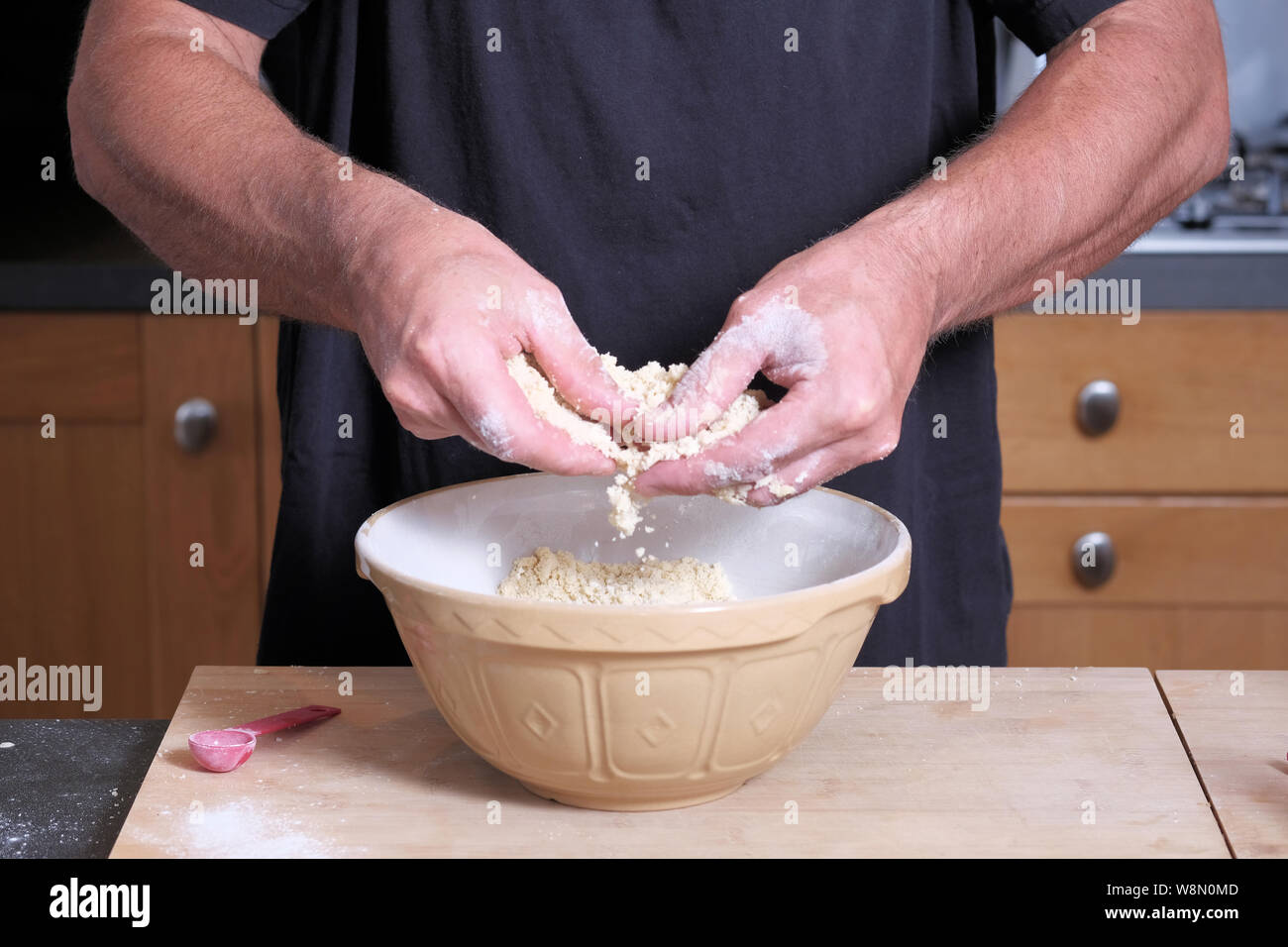 Un homme cuisinier ou baker le mélange d'un mélange à gâteau gâteau dans un bol Banque D'Images