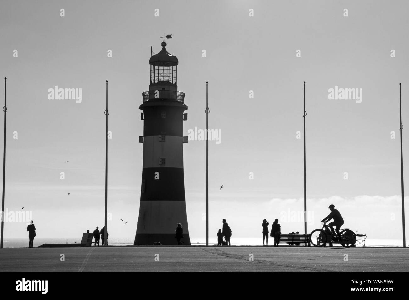 Smeaton's Tower sur Plymouth Hoe avec silhouettes de piétons, visiteurs et un cycliste Banque D'Images