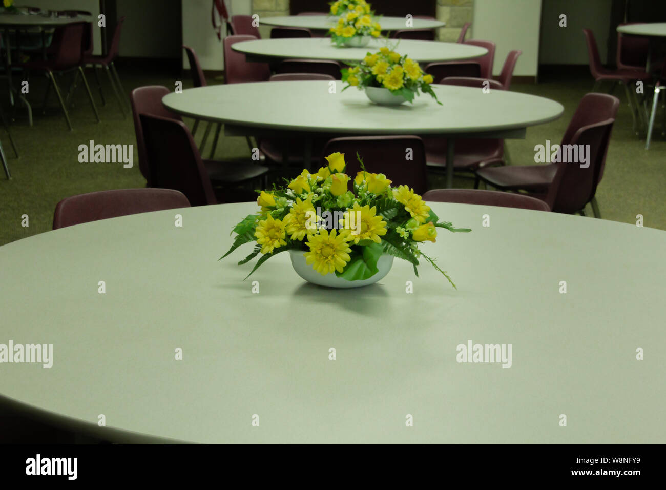 Salle de réunion vide avec des tables rondes avec des arrangements de fleurs sur la table. Banque D'Images