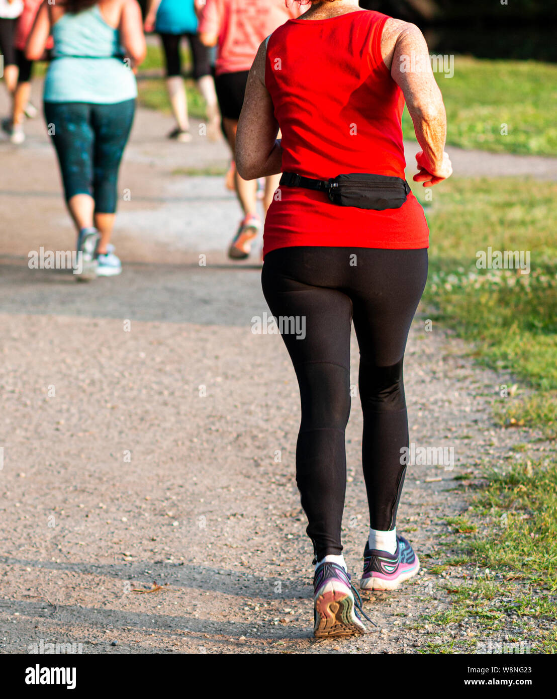 Vue arrière du milieu du peloton d'exécution d'une course de 5 km sur un chemin de terre dans un parc local. Banque D'Images