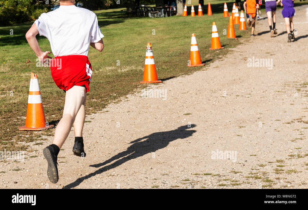 Un lycéen racing dans une course de cross-country est la chasse aux dirigeants qu'ils se rapprocher de la ligne d'arrivée à Sunken Meadow State Park. Banque D'Images