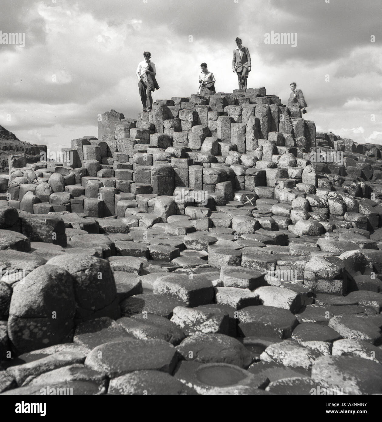 Années 1950, historique, les visiteurs sur les colonnes de basalte hexagonal à la Giant's Causeway, Antirm Co., l'Irlande du Nord, Royaume-Uni. Au nord de l'océan Atlantique, sur la côte de causeway, ils sont le résultat d'une ancienne fissure volcanique éruption. Banque D'Images