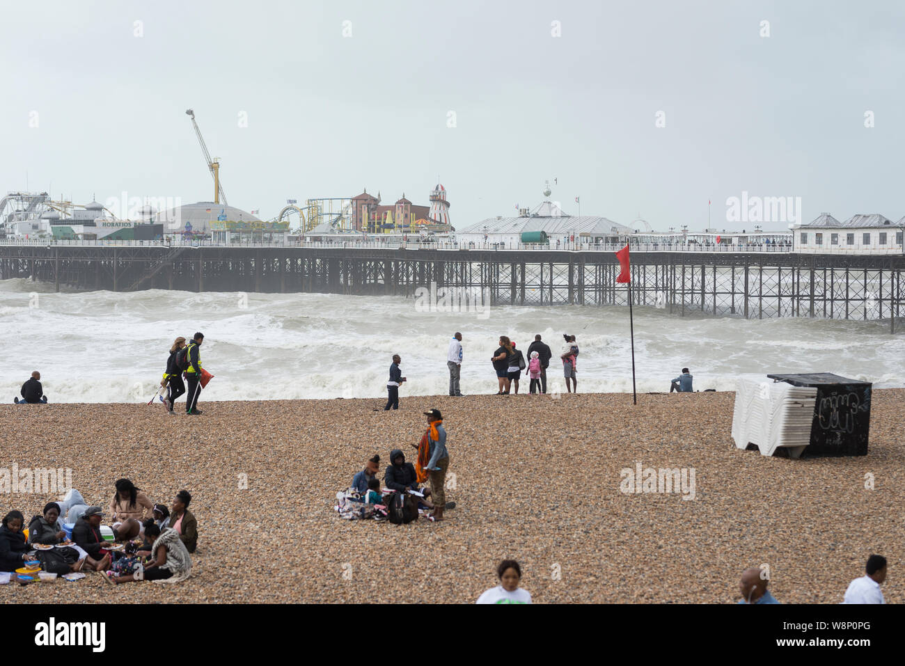 Brighton, Angleterre, Royaume-Uni. 10 août, 2019. Brighton, East Sussex. 10 août 2019. Météo britannique. Une bande de basse pression est en train de s'étendre à travers le pays, apportant des vents violents et d'énormes vagues qui à front de mer de Brighton, en tant que spectateurs à regarder et encore essayer de profiter de la plage à cet effet pour la saison et les conditions météorologiques. UK avertissements météo pour vent ont été émis à travers le pays par le Met Office, avec des rafales allant jusqu'à 60 mi/h sur la côte sud. Credit : Francesca Moore/Alamy Live News Banque D'Images