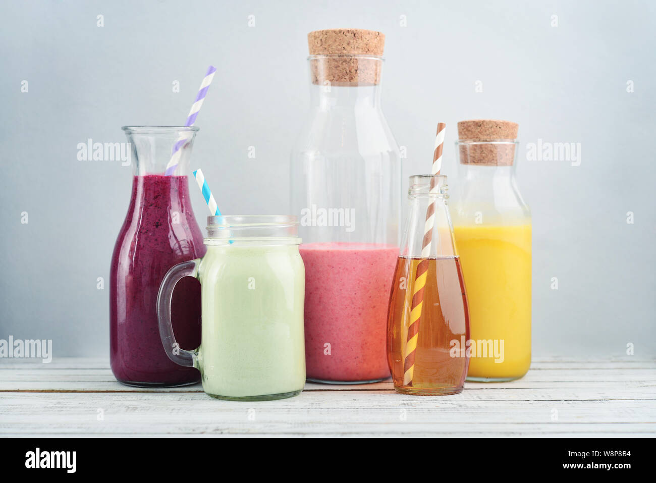 Orange, vert et rouge des smoothies et des jus dans un pot en verre sur un fond bleu. Banque D'Images