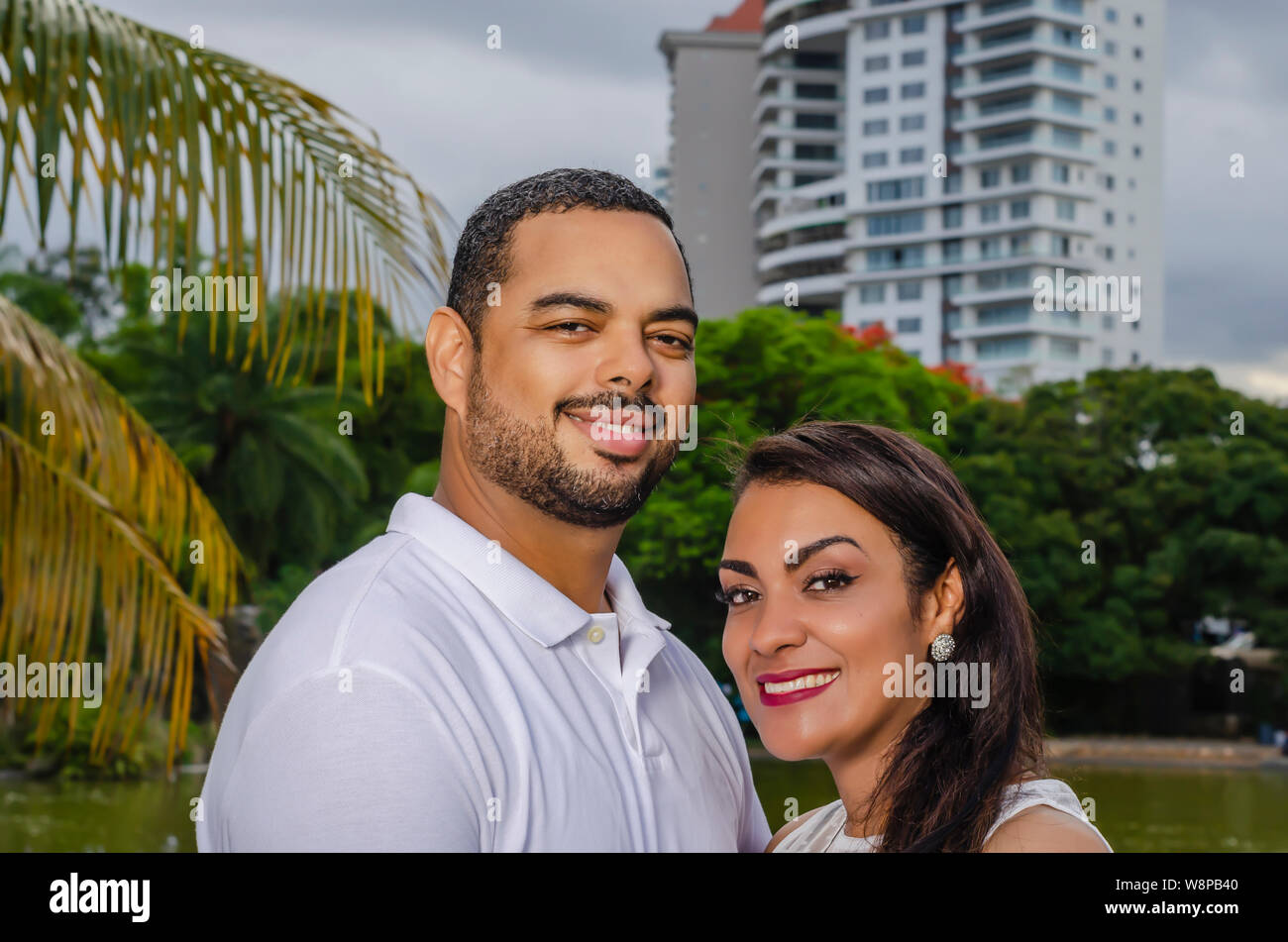 Couple de jeunes hommes et femmes d'Amérique latine et heureux à l'extérieur en portrait, ensemble dans un parc, ju à la fois rire et romantique hugging Banque D'Images