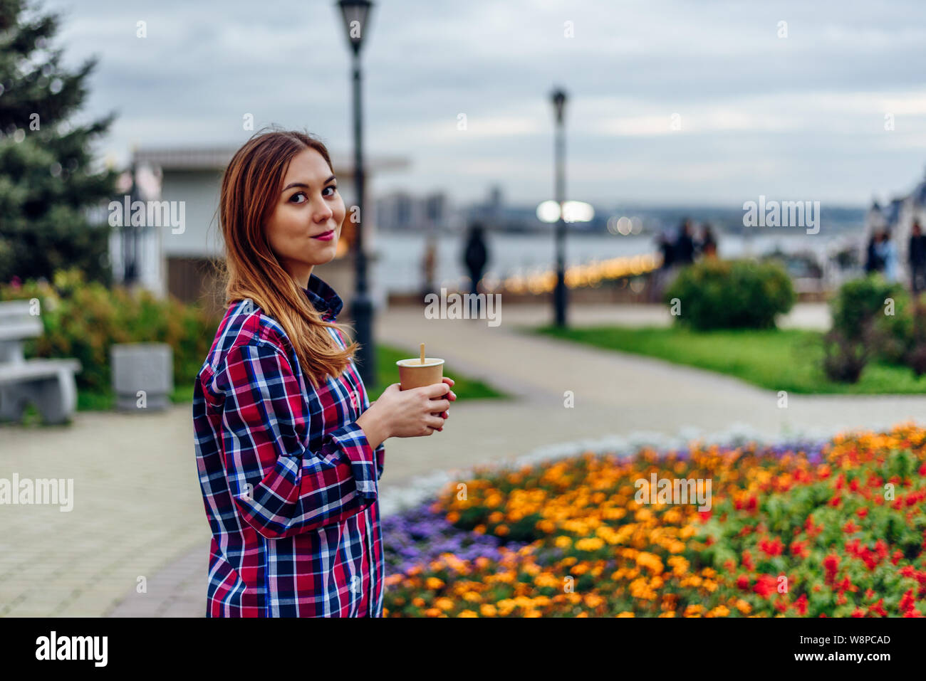 Café sur le rendez-vous. Belle jeune femme holding Coffee cup and smiling in the park Banque D'Images