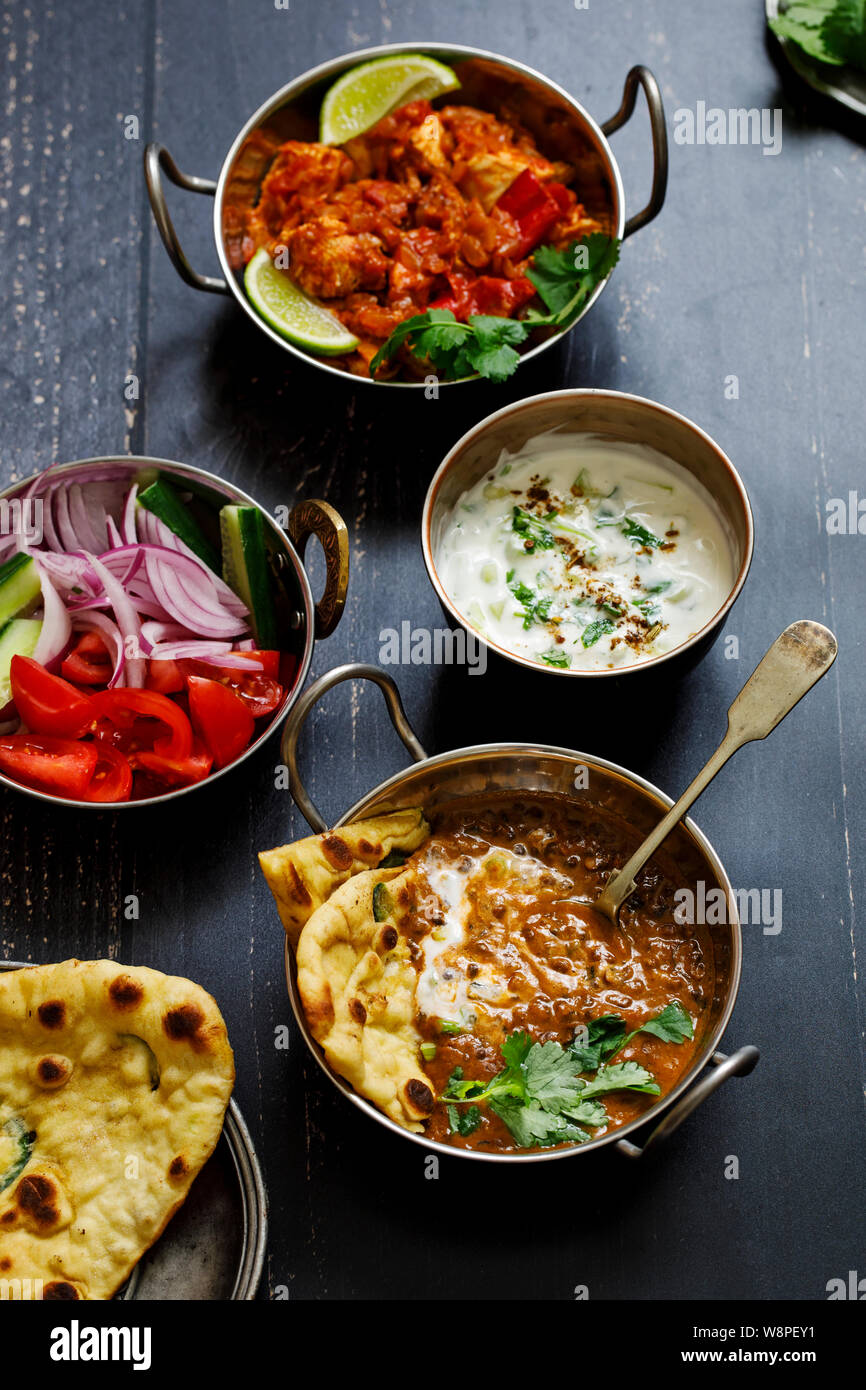 Repas curry indien noir avec les lentilles dal, épicé de pommes de terre, riz, pain naan et raita Banque D'Images