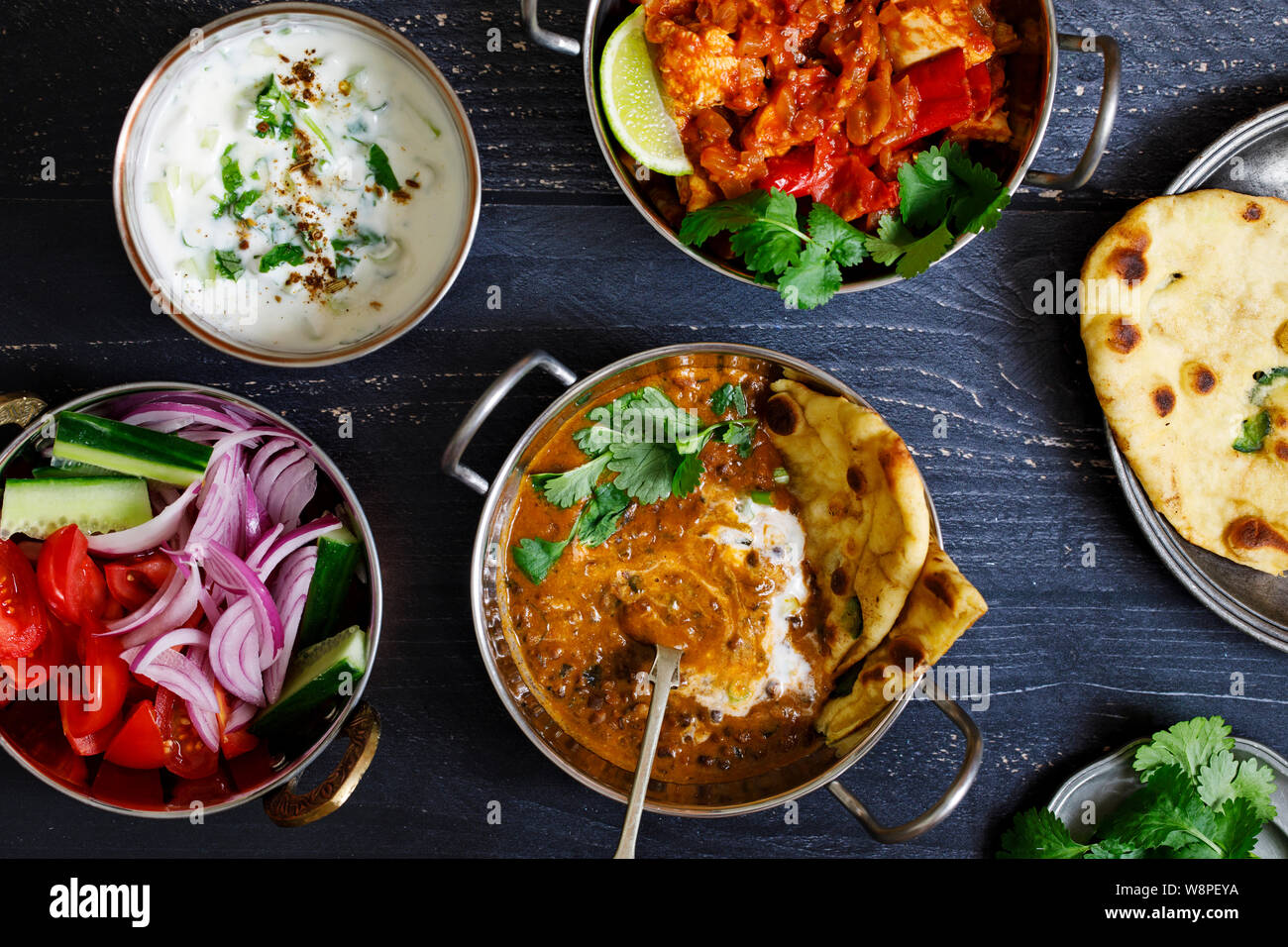 Repas curry indien noir avec les lentilles dal, épicé de pommes de terre, riz, pain naan et raita Banque D'Images