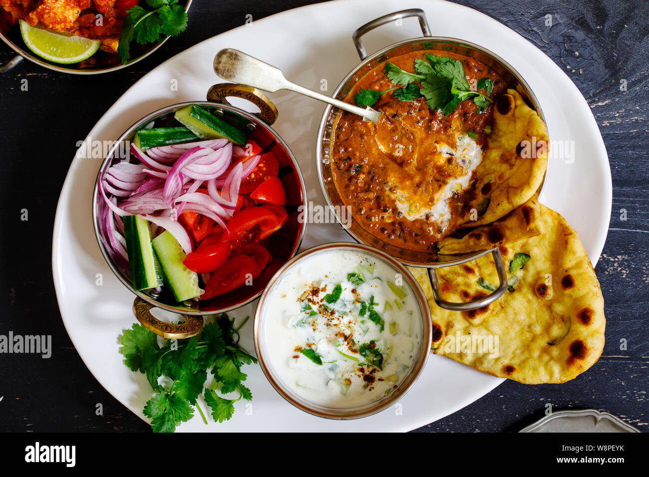 Repas curry indien noir avec les lentilles dal, salade, pain naan et raita Banque D'Images