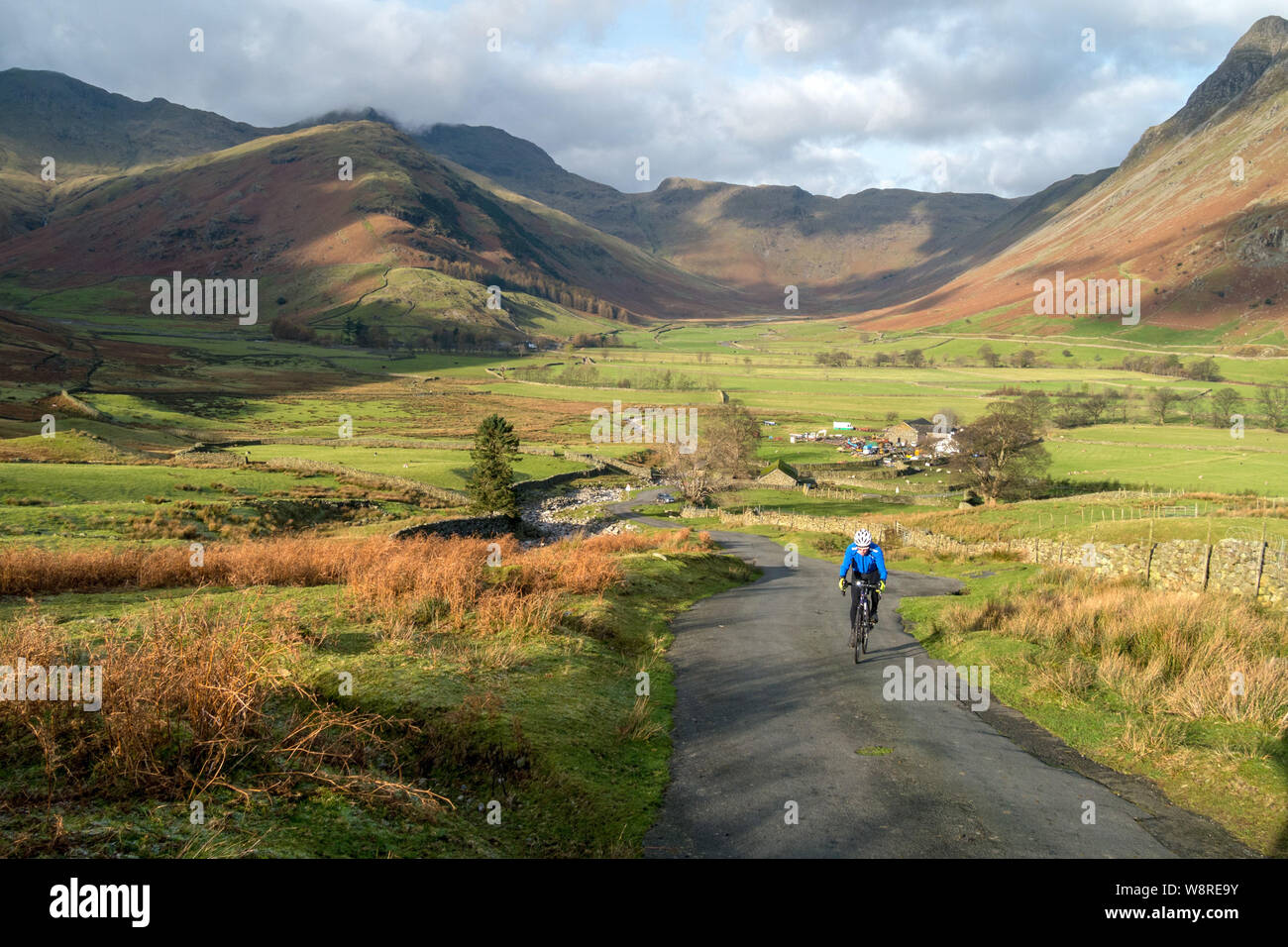 Vélo Cycliste solitaire monte raide jusqu'à la route à voie unique avec Mickleden au-delà de la vallée de Langdale, Parc National de Lake District, Cumbria, England, UK Banque D'Images